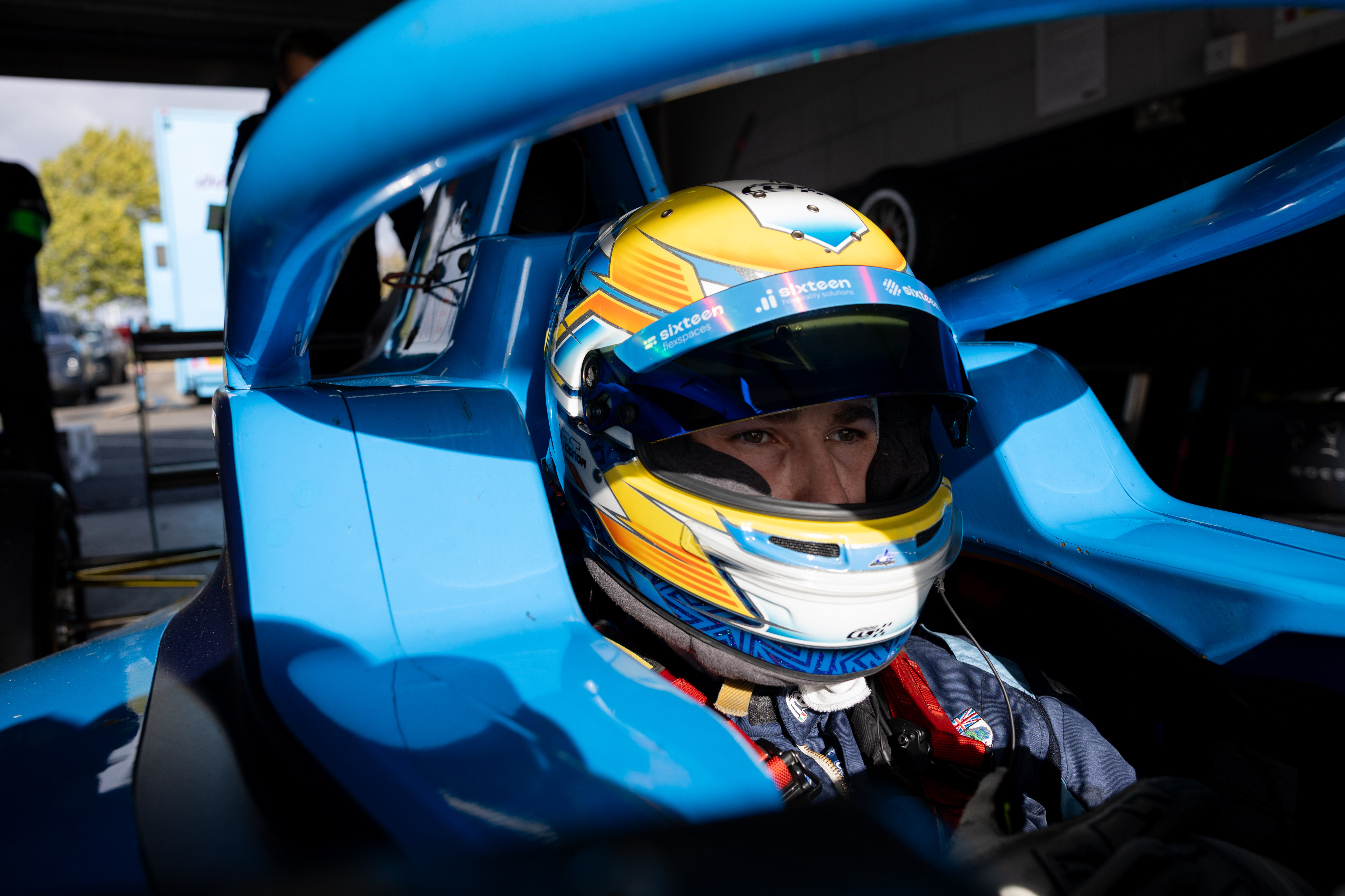 Conor Grant in the cockpit wearing his yellow and blue racing helmet